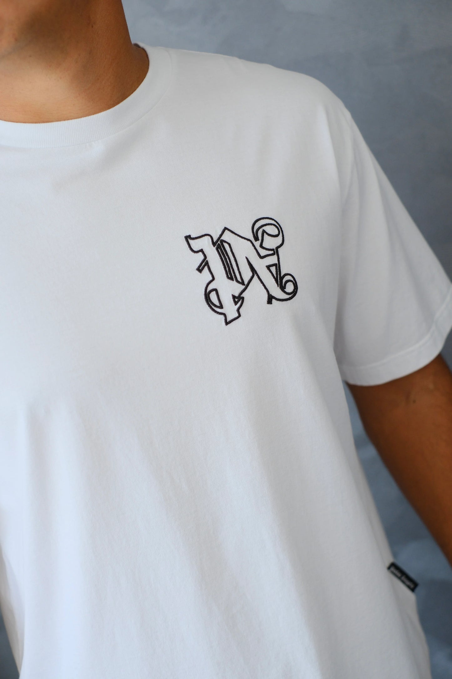 Camiseta blanca de hombre con letra gótica bordada en el pecho, estilo urbano