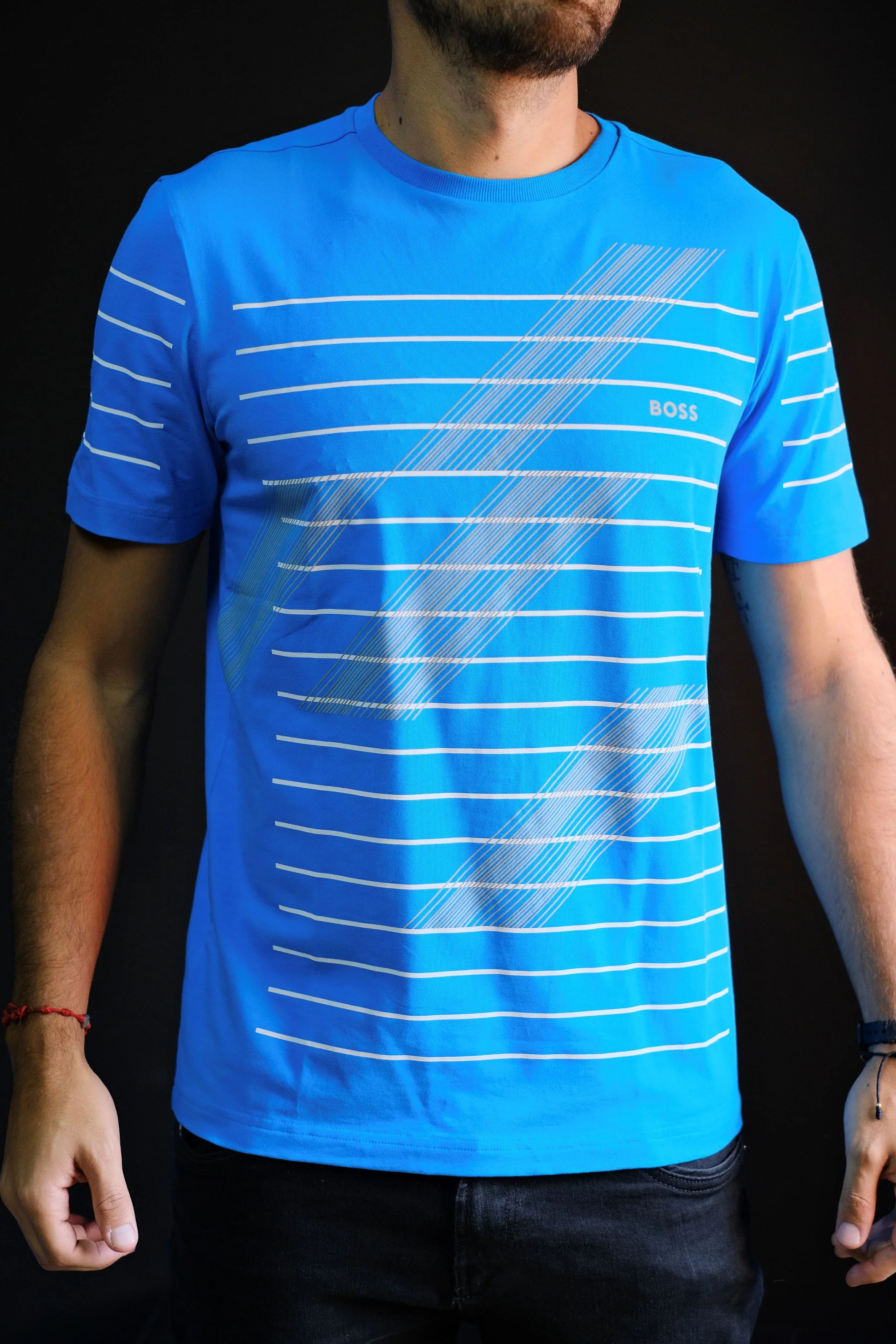 Camiseta azul para hombre con rayas blancas y logo, fondo negro, estilo casual.
