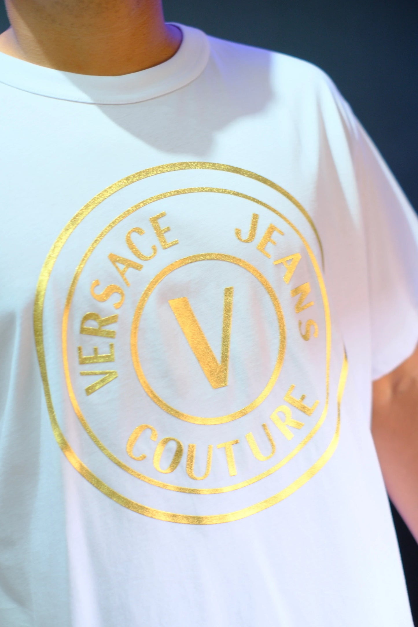 Camiseta blanca con logo dorado de Versace Jeans Couture estampado en el pecho.