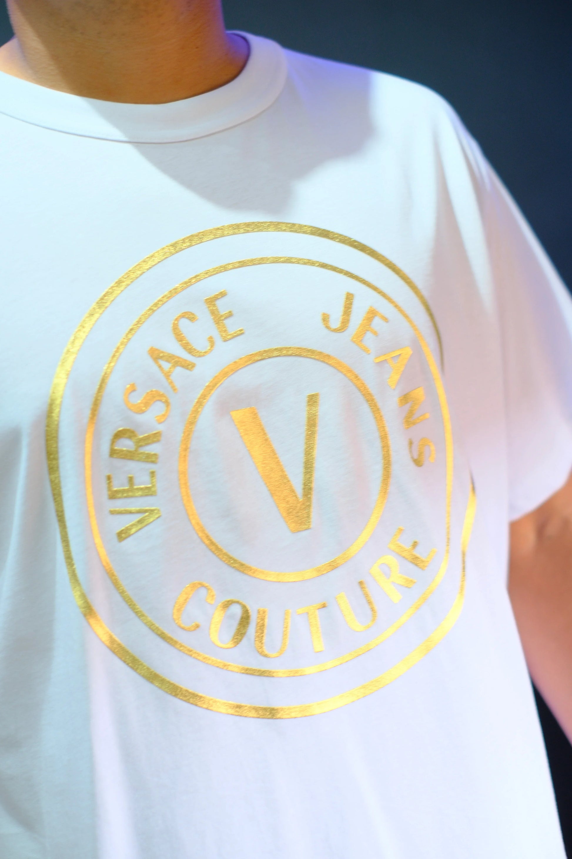 Camiseta blanca con logo dorado de Versace Jeans Couture estampado en el pecho.