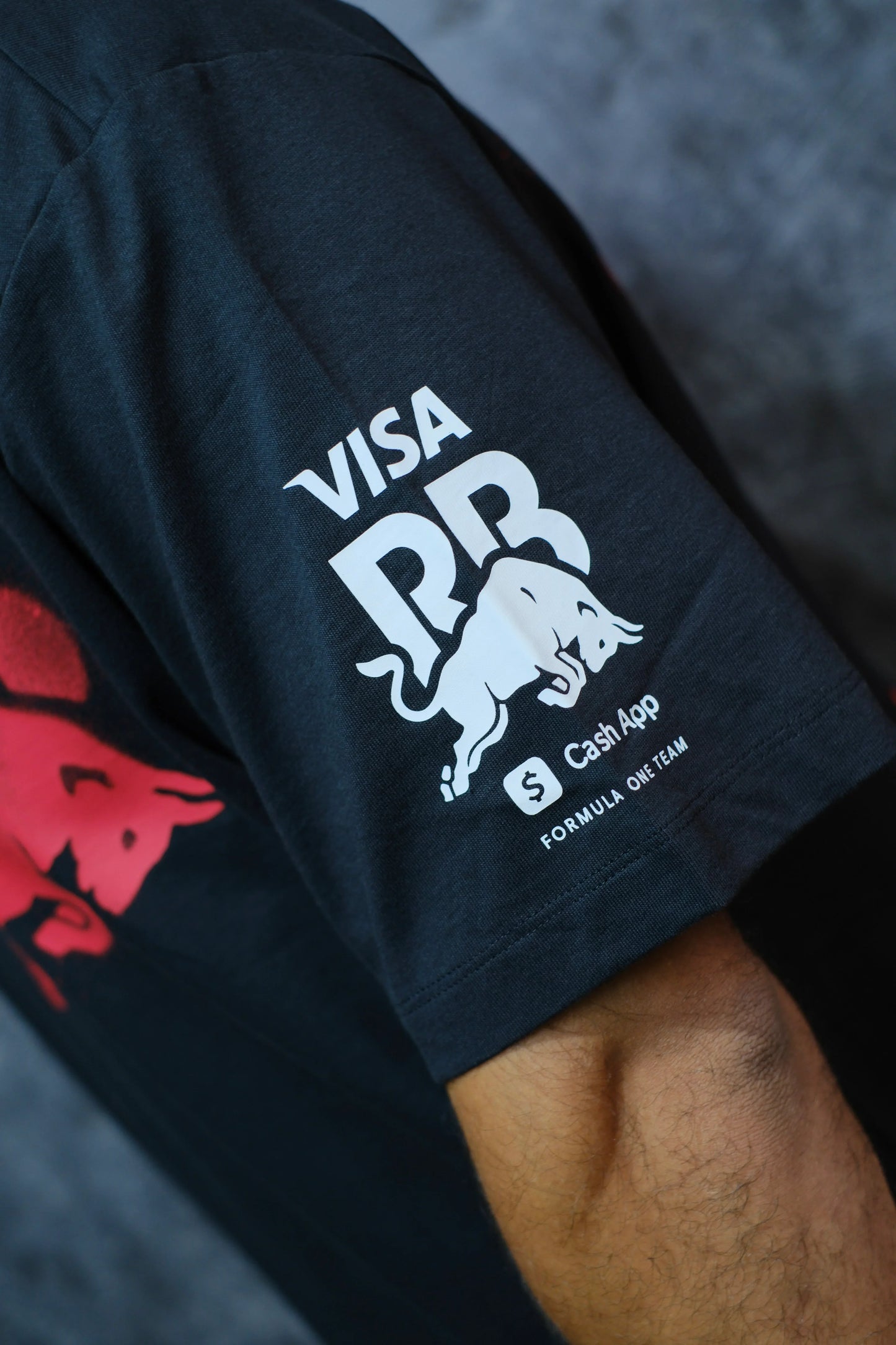 Manga de camiseta negra con logos de Visa, Red Bull, Cash App y detalles de Fórmula 1