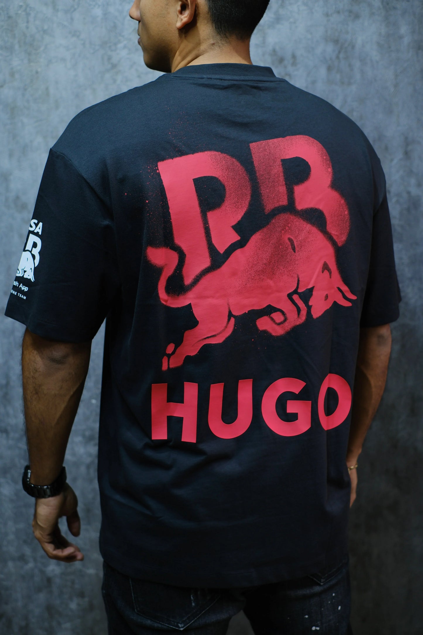 Camiseta negra con diseño de toro rojo, letras RR y nombre HUGO en la espalda, moda urbana.