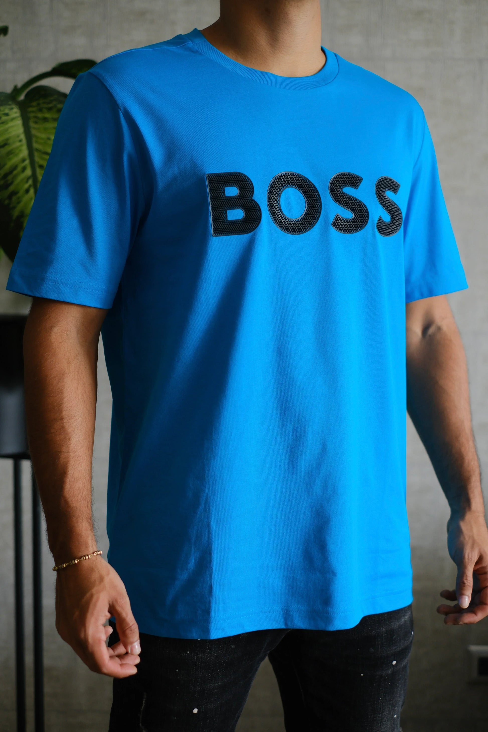Camiseta azul de hombre con letras BOSS en negro, fondo interior moderno, estilo casual