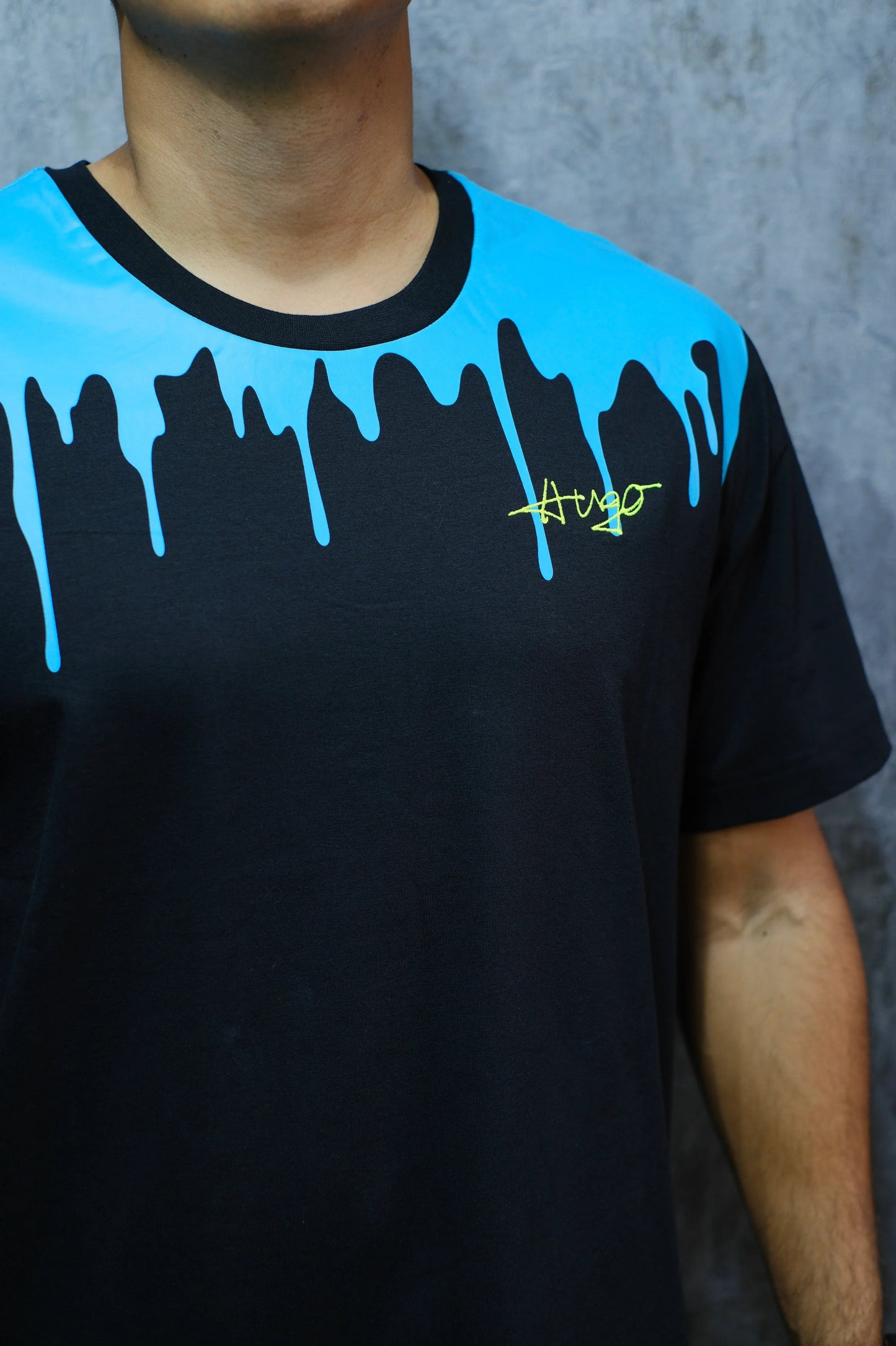 Camiseta negra con diseño azul en efecto goteo y detalles de texto amarillo, estilo urbano.
